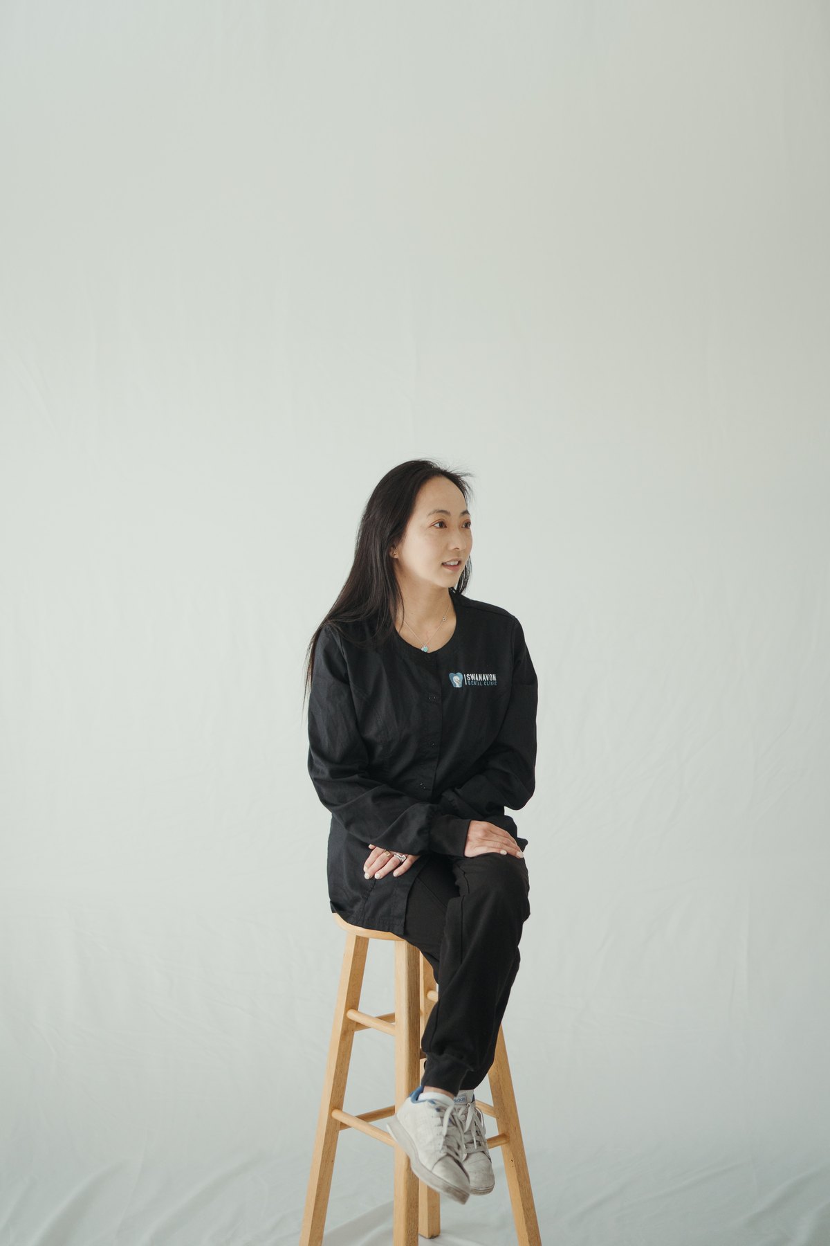 Full-length portrait of Dr. Tammy Chu seated on a wooden stool