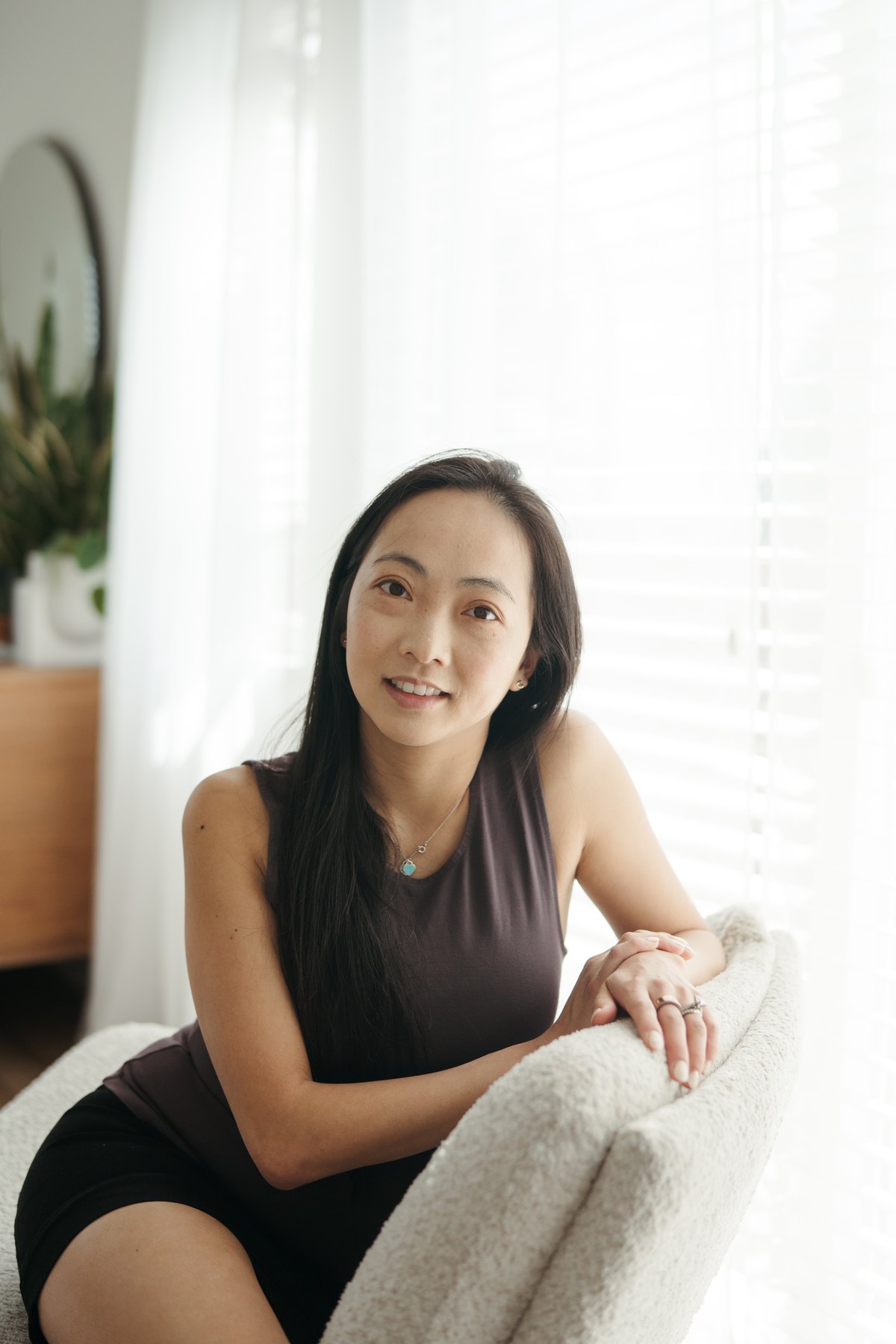 Dr. Tammy Chu leaning on the back of an armchair by a bright window